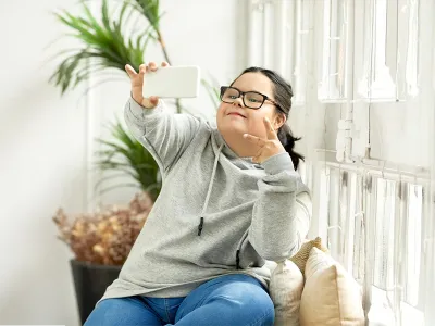 Young girl with down syndrome taking a selfie with a cellphone
