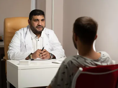 A man sit behind a table explaining paperwork to another man