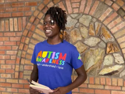 Tierra smiling to the camera with a purple shirt promoting Autism Awareness
