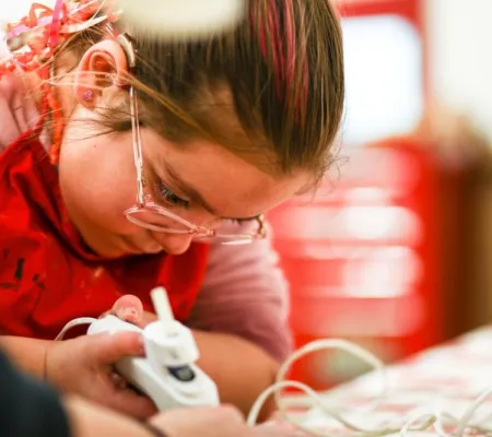 Girl uses a glue gun while crafting. 