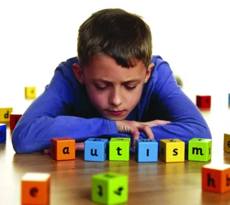 A boy playing with color blocks with the letters than read autism