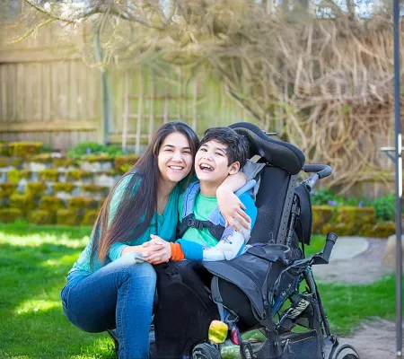 A woman and a child in a wheel chair laughing