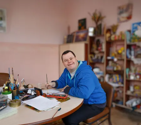 Young many with Down Syndrome smiling and drawing a picture