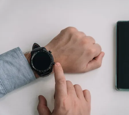 A hand with a smartwatch and phone