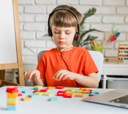A kid playing with blocks wearing headphones