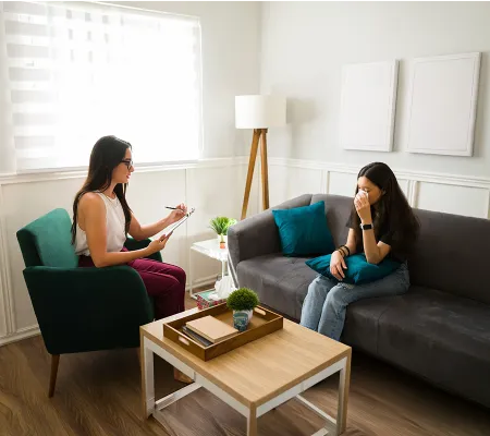 A therapist talking with a young woman in a sofa