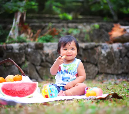 A toddler eating fruits in the park