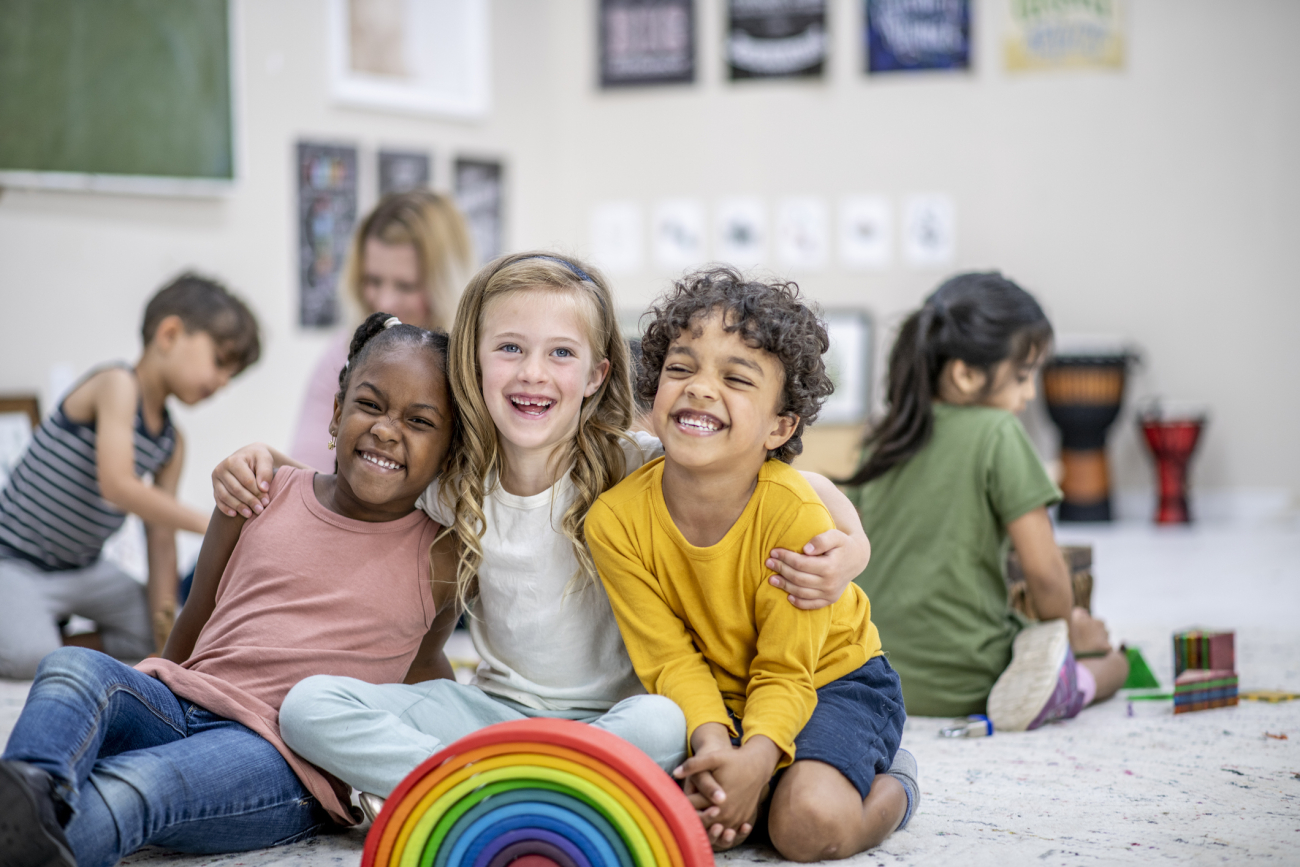 Three children sitting in a classroom and smiling