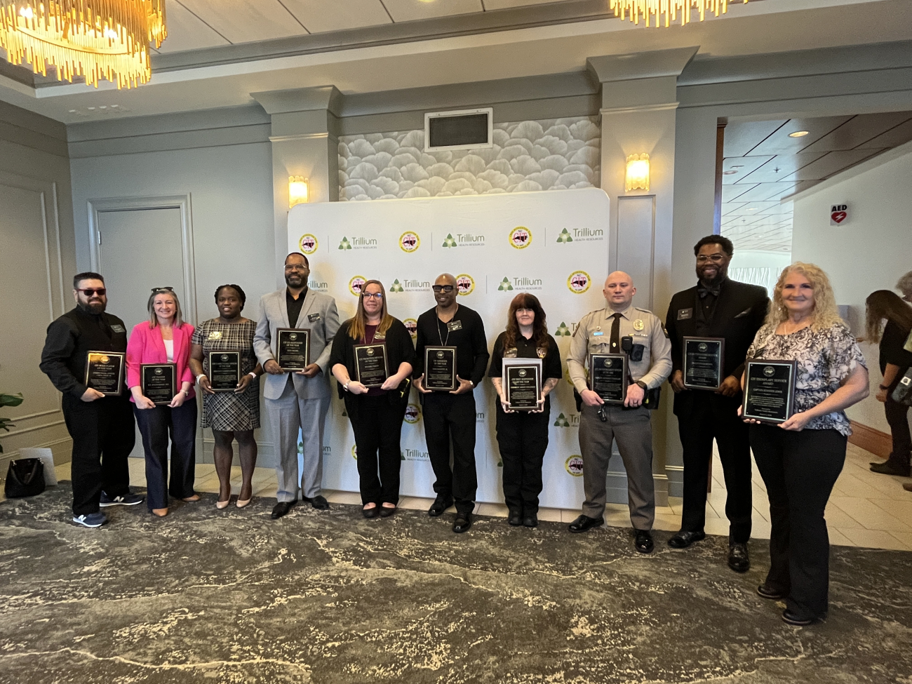 A group of people posing infront the camera with CIT award on their hands