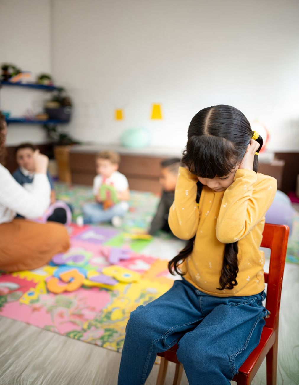 a girl with a yellow sweater covering her ears
