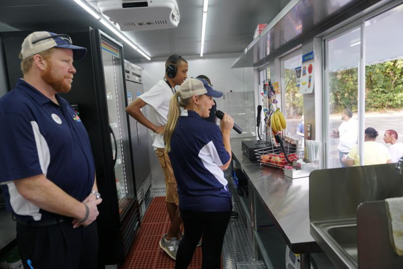 Woman speaks on microphone inside Senseable Snacks food truck. The Senseable Snacks food truck provides people with intellectual and developmental disabilities employment serving healthy snacks to their communities. 